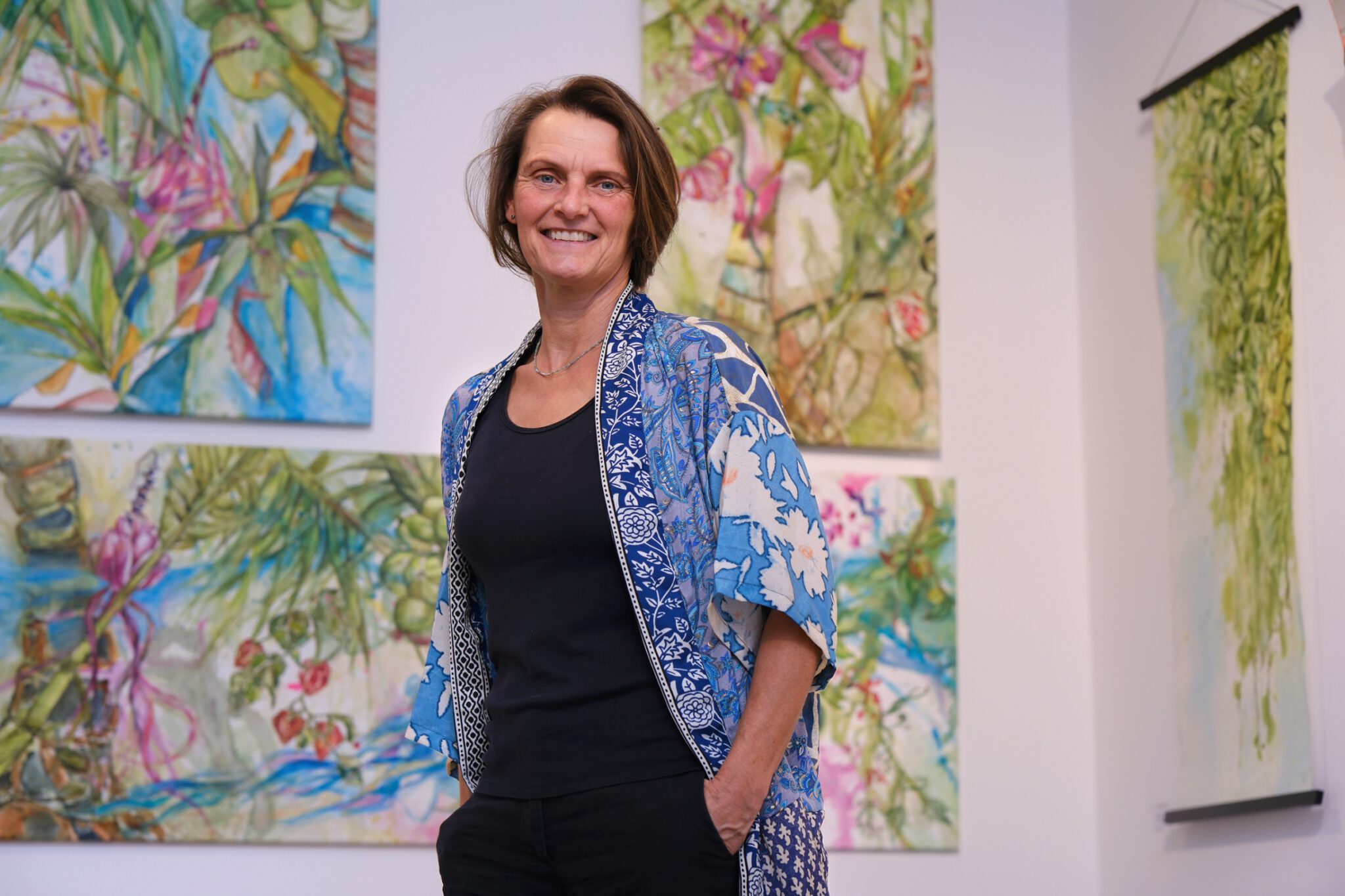 Kerstin Mempel in der Ausstellung vor ihren Bildern stehend.