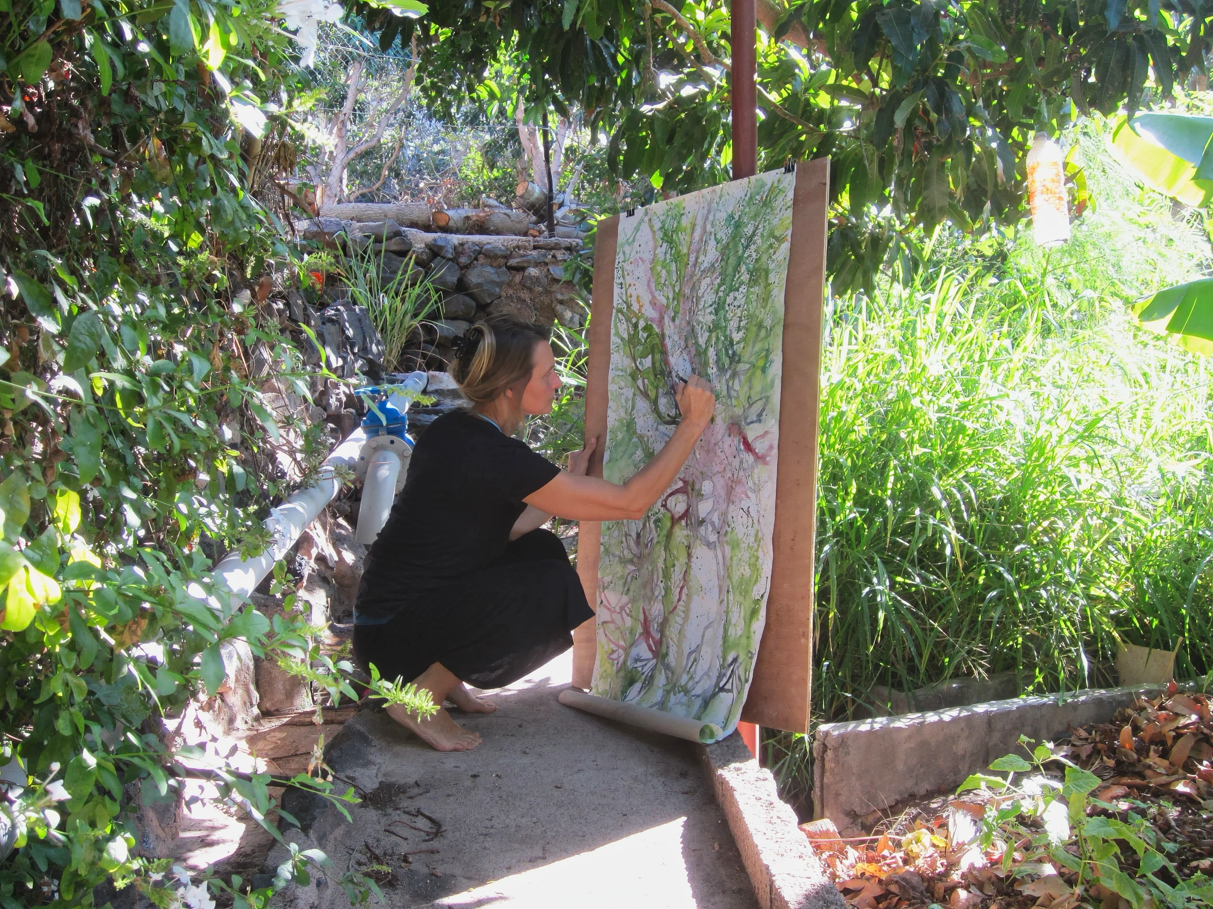 Kerstin Mempel hockend vor einem großformatigen Aquarell auf Leinwand, (ca. 60 x 150 cm), Fotografie. Gomera.